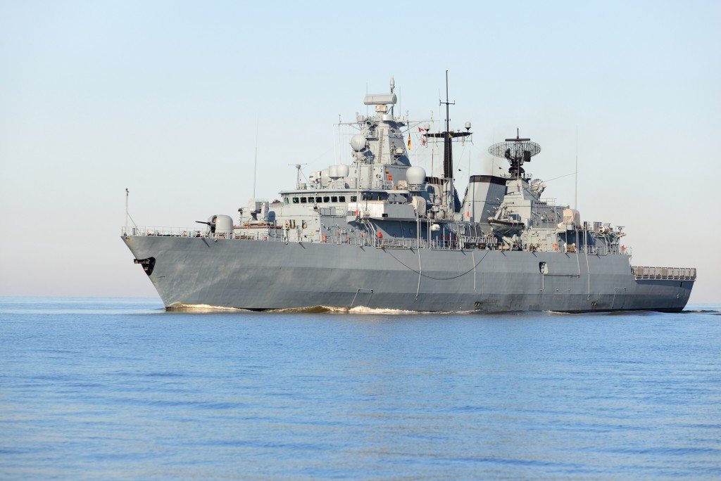 Grey modern warship sailing in still water